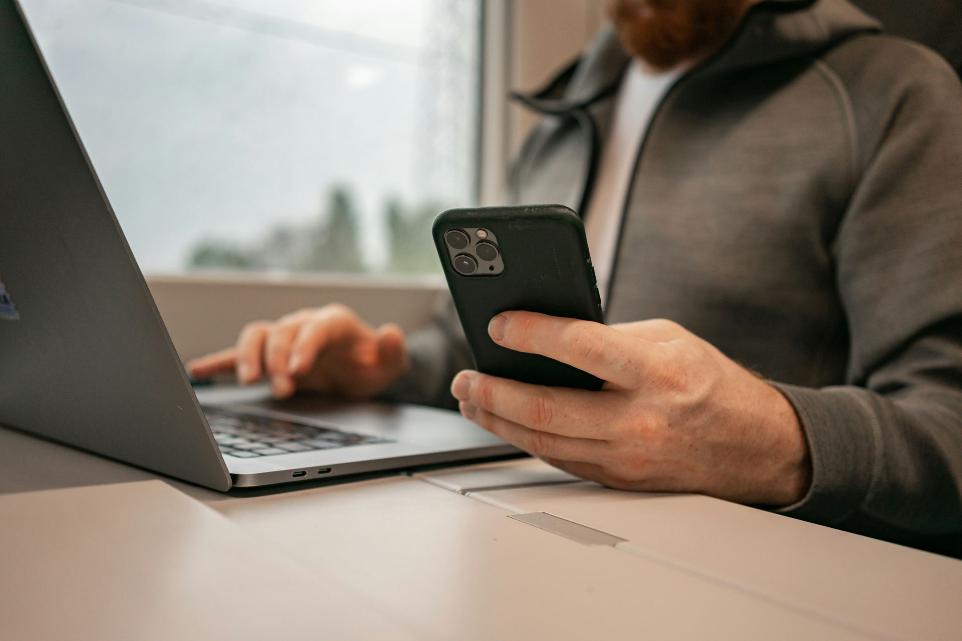 man checking phone and laptop